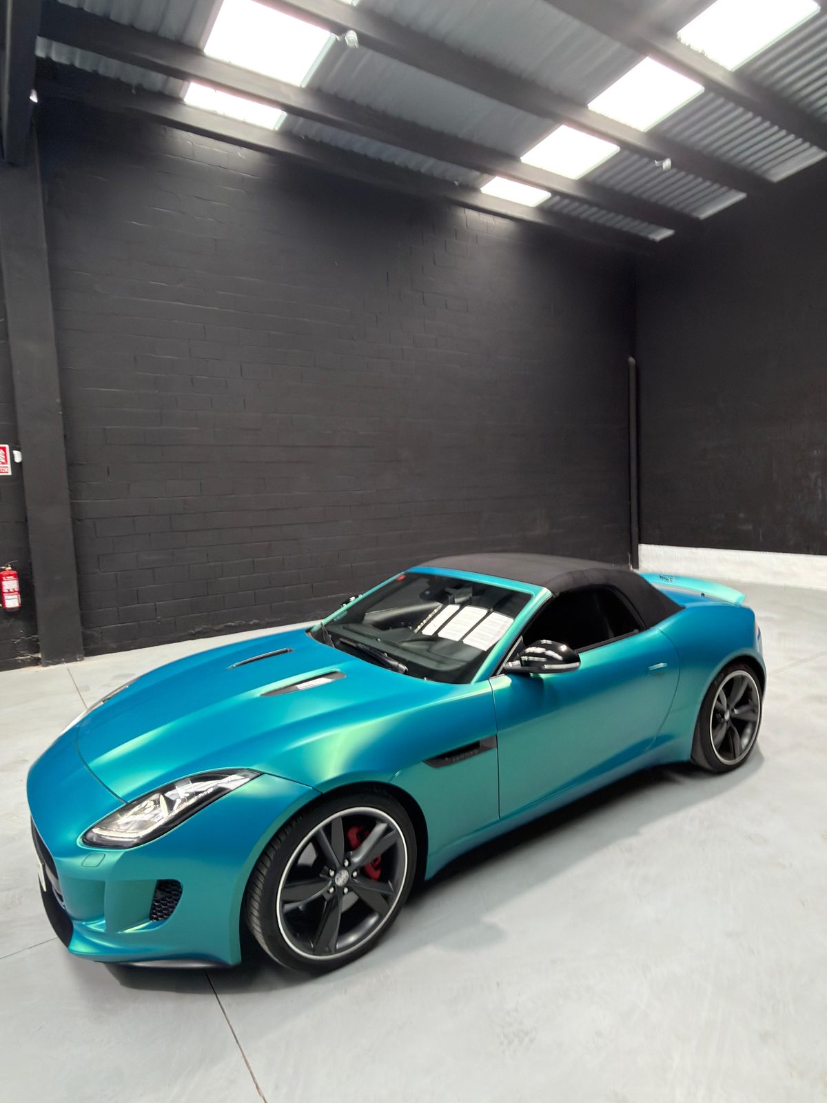 Jaguar F-Type Convertible en vinilo turquesa, capota negra, lateral delantero