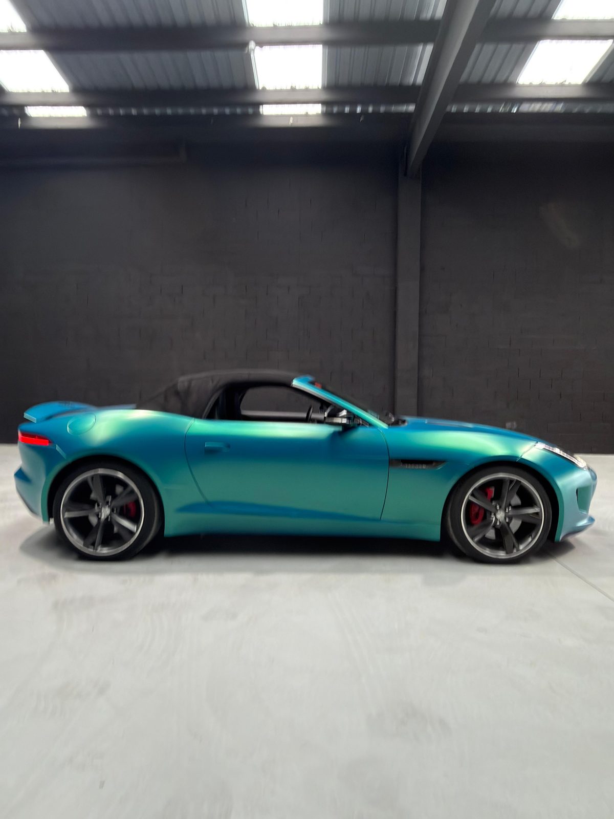 Jaguar F-Type Convertible en vinilo turquesa, capota negra, perfil