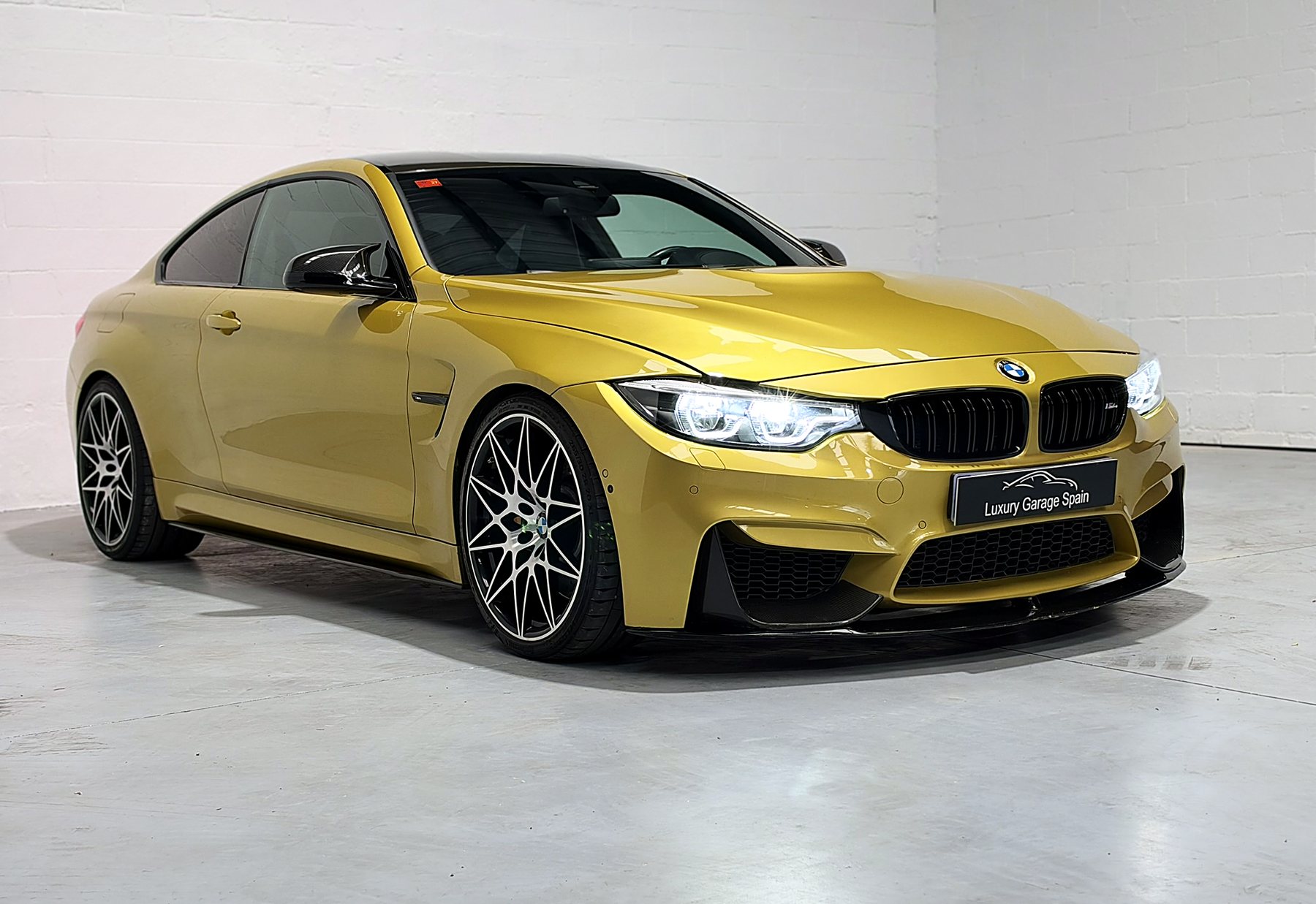 BMW M4 amarillo en tres cuartos delanteros, con los faros encendidos y llantas de radios en Y, en nuestro local