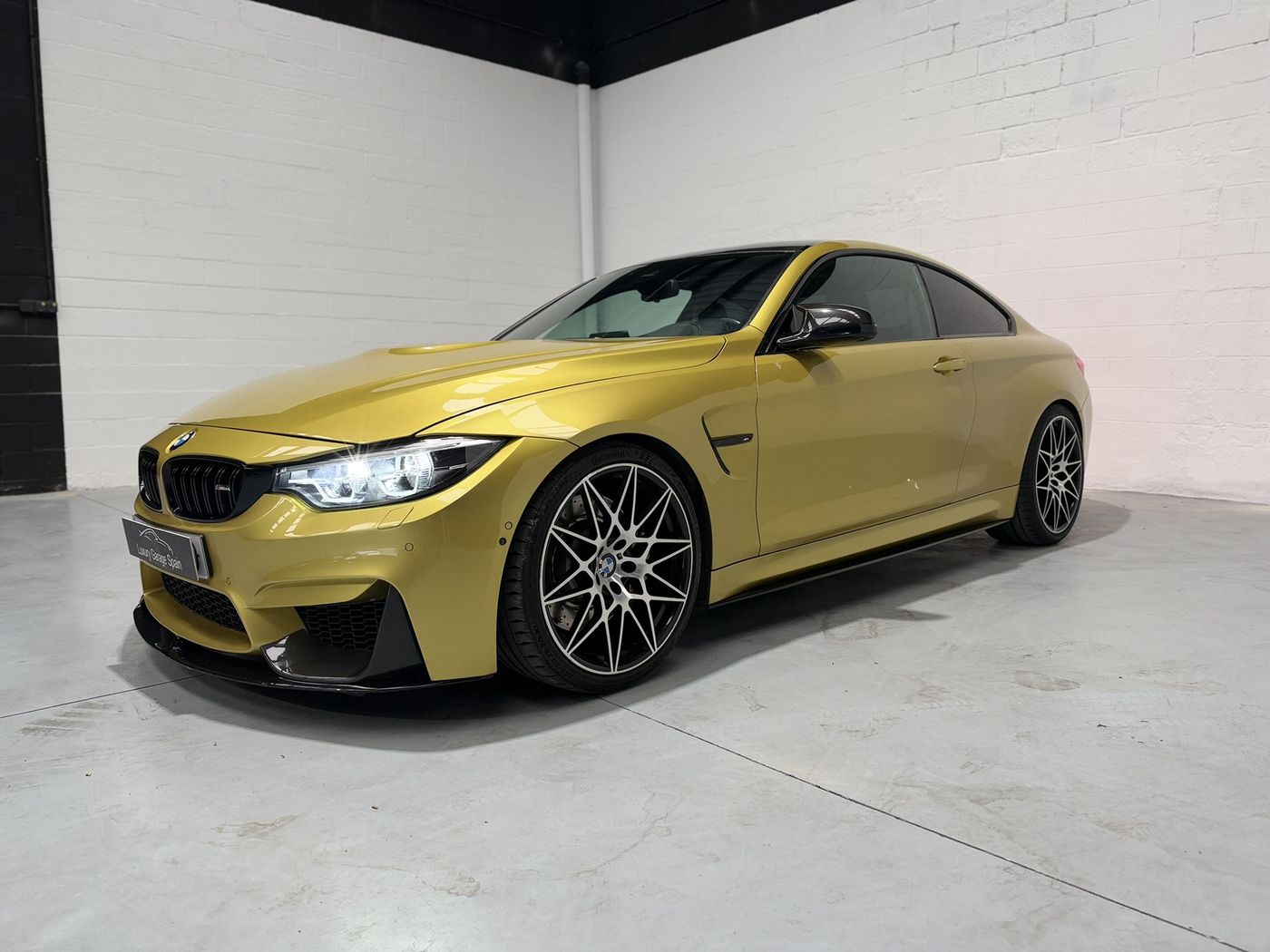 BMW M4 amarillo en tres cuartos delanteros, con la llanta en primer plano