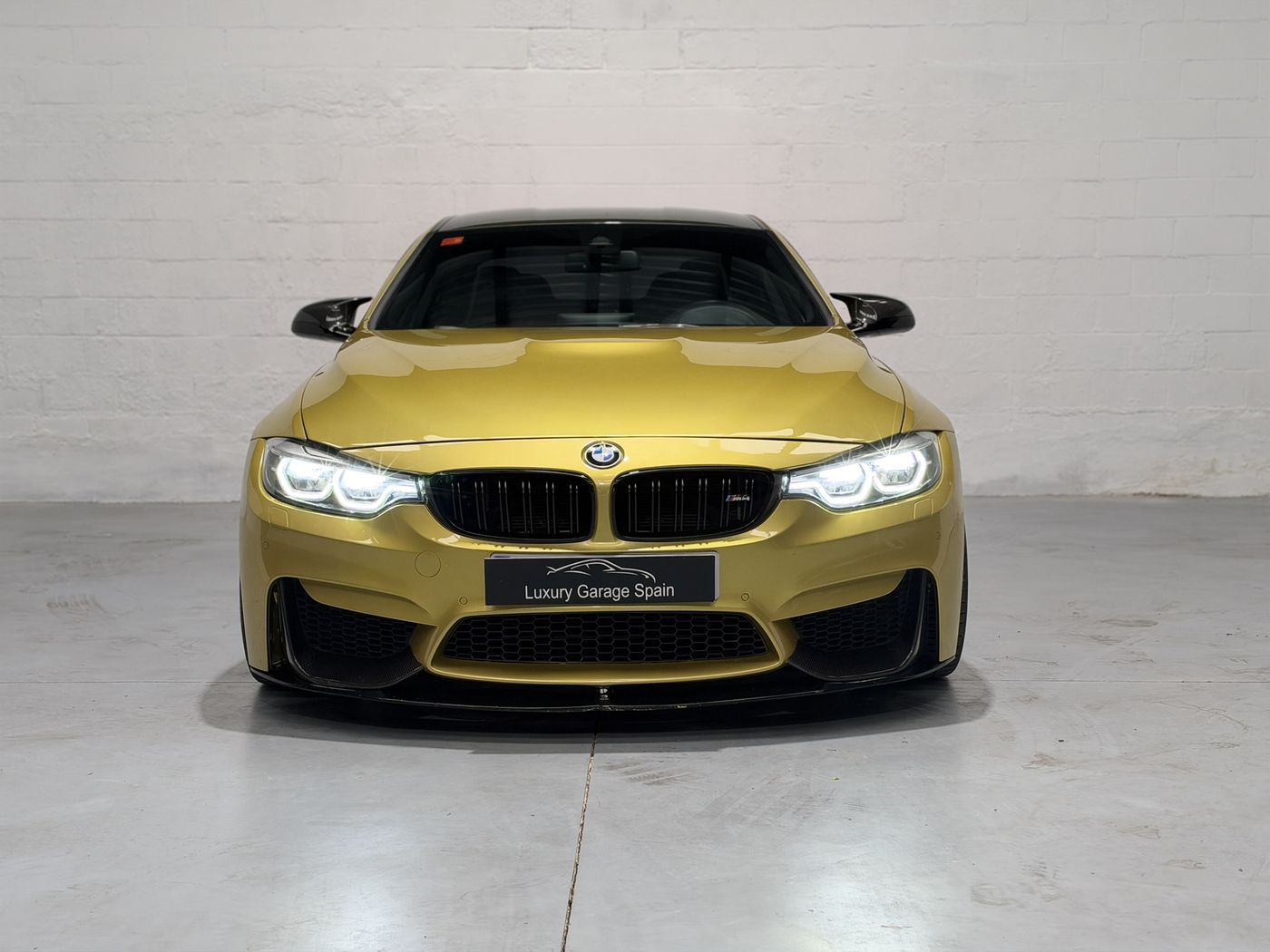 BMW M4 amarillo, vista frontal con los faros encendidos