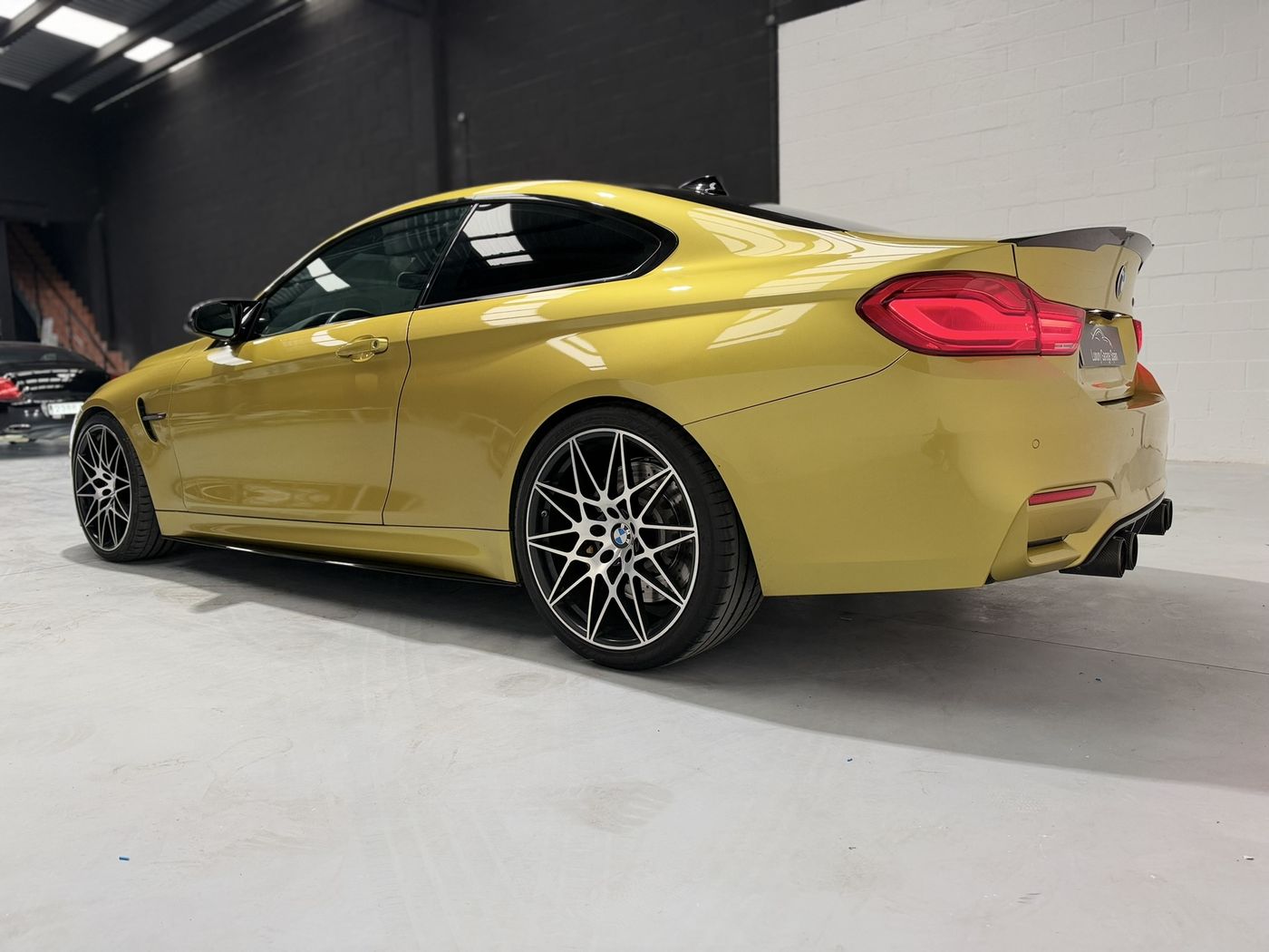 BMW M4 amarillo en tres cuartos traseros desde el otro costado