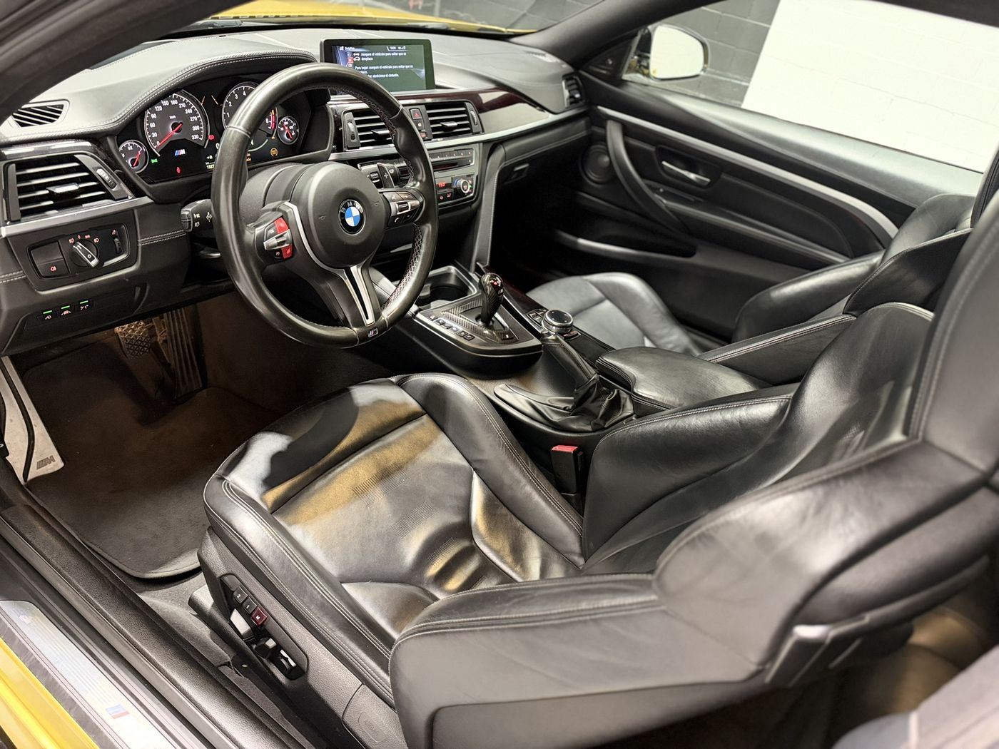 Interior del BMW M4: puesto de conducción con volante M, asientos de cuero negro y pantalla