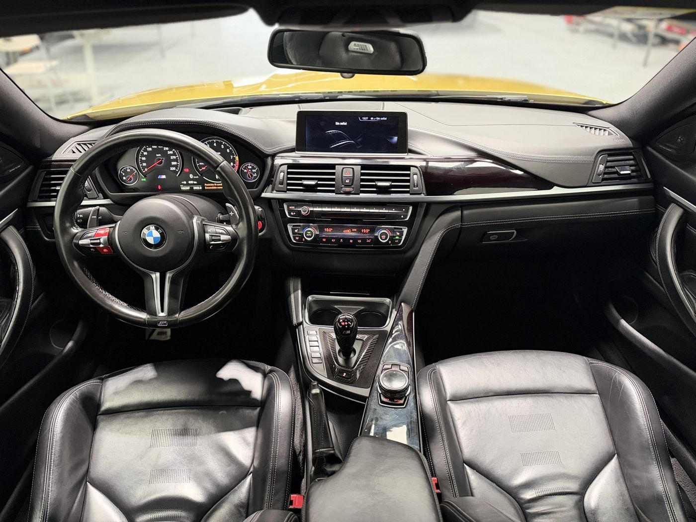 Vista cenital del salpicadero del BMW M4: volante M, pantalla central y consola con pomo de cambio