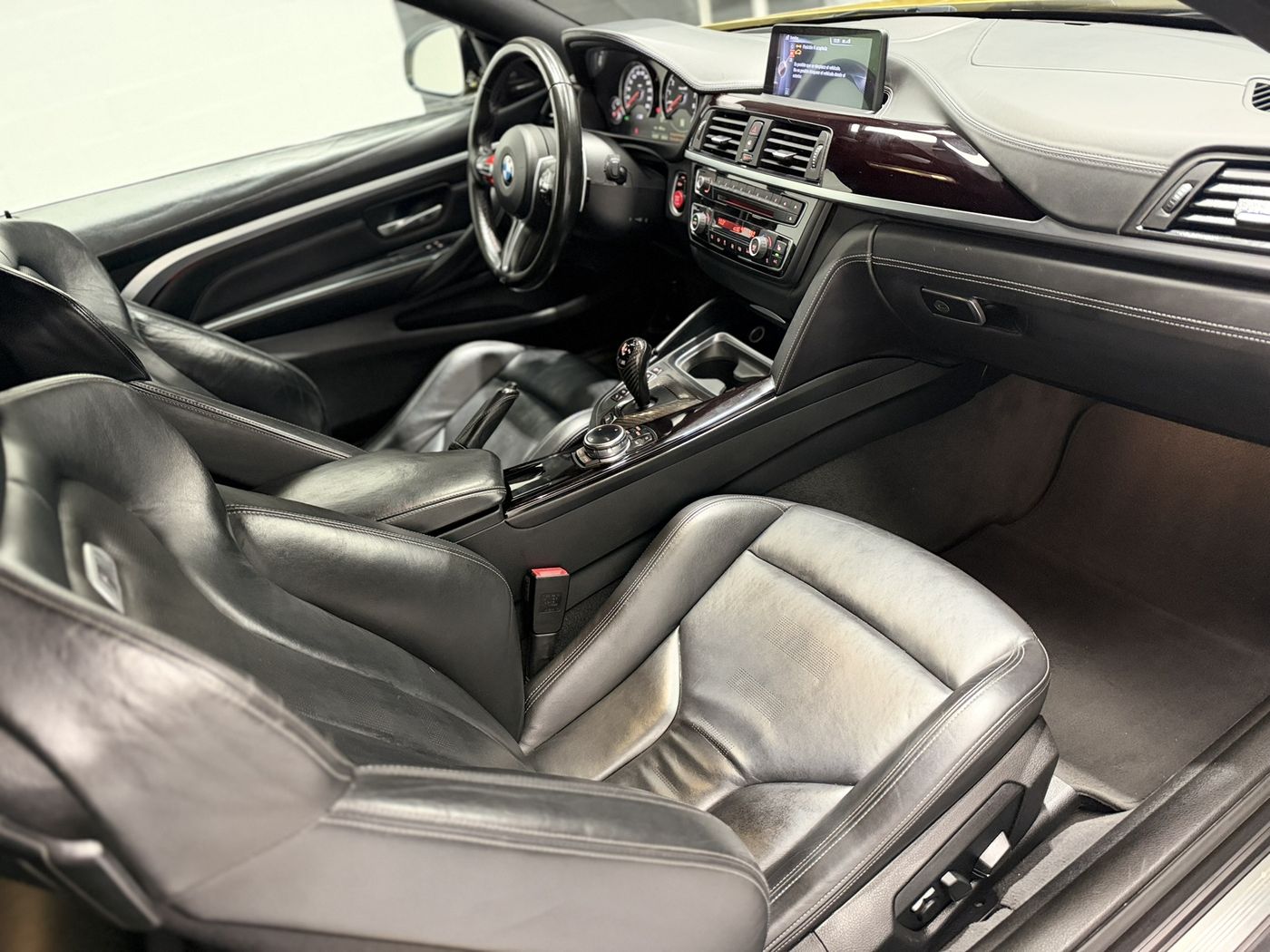 Interior del BMW M4 visto desde el lado del acompañante: consola central y asientos deportivos de cuero