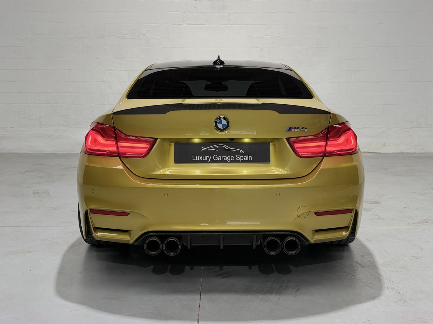Vista trasera del BMW M4 amarillo con alerón de carbono y escape cuádruple