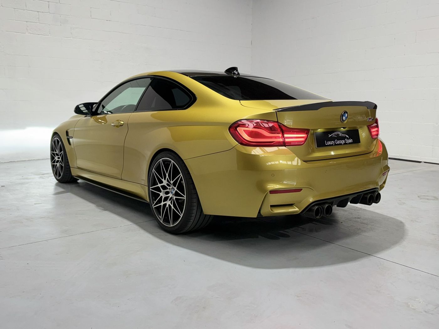 BMW M4 amarillo, tres cuartos trasero izquierdo con llantas de radios en Y